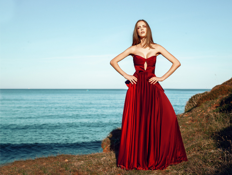 Woman in Red Dress Standing on Cliff